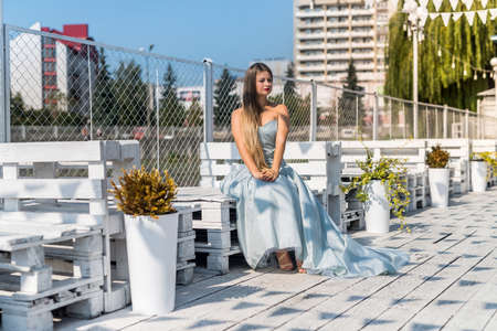 Slim young woman in summer dress posing at city landscapeの写真素材