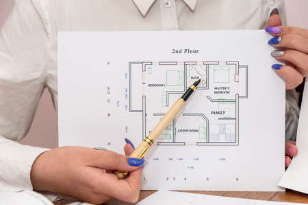 Female hands with pen pointing at house project
