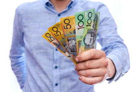Male hand offering australian dollar banknotes isolated on whiteの写真素材