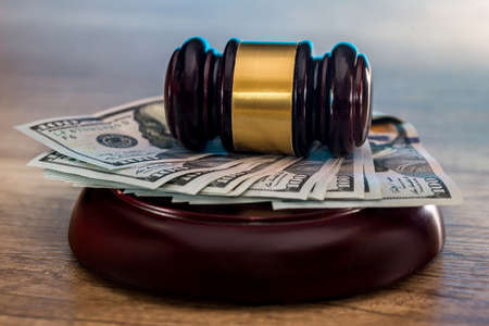Judge's gavel with dollars in roll and golden coins