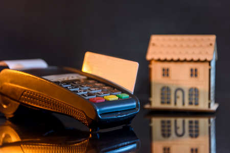Terminal with credit card and wooden house modelの写真素材