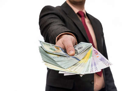 Male hand offering pile of dollar and euro banknotes