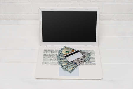 Dollar banknotes on laptop keyboard and credit cardの写真素材