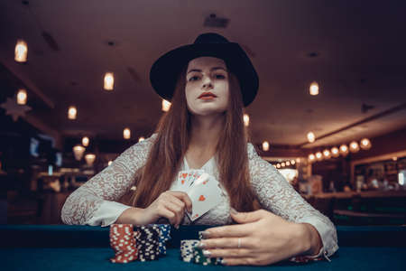 Woman in hat with playing cards and poker chips in casino