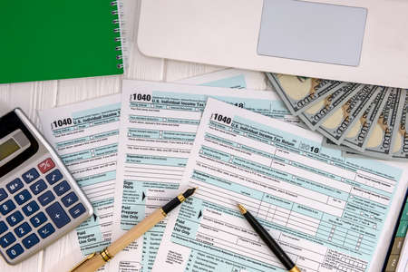 1040 form with laptop and dollar banknotesの写真素材