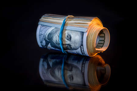 Roll of hundred dollar banknotes isolated on black