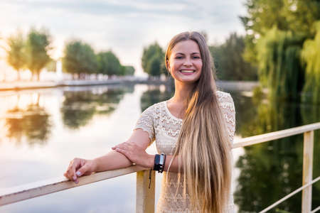 Beautiful young woman posing in long dress on quay