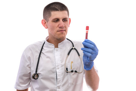 Young doctor in white uniform holding test tube with blood sample isolated on white background.の写真素材