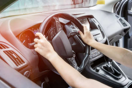Female hands with steering wheel close up. Woman driving car and holding tight car steering wheelの写真素材