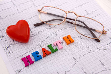 Stethoscope on cardiogram on table close up