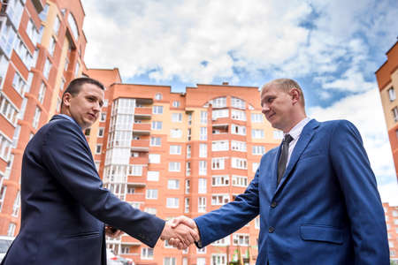 Two businessmen handshaking before new building outdoorsの写真素材