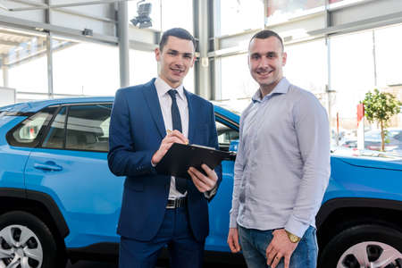 Salesman working with client in showroom, car buy operationの写真素材