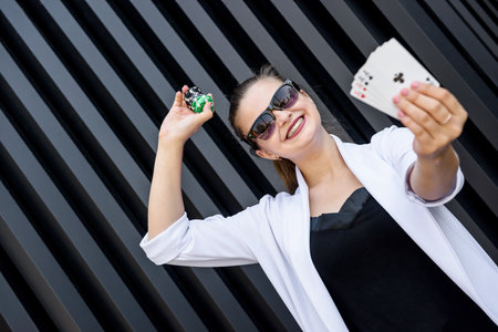 Dealer with poker chips and playing cards on abstract background. Woman in sunglasses holding casino...