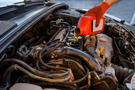 Male hands with oil bottle above car engineの写真素材