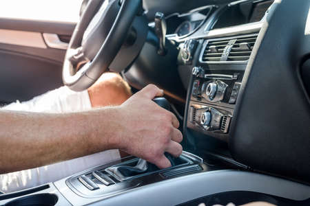 Male hand on transmission gear inside car. Close view of male hand with car interior