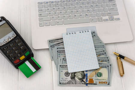 Laptop with banking terminal and dollar banknotes