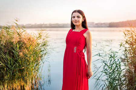 Brunette woman in a red dress on the seashoreの写真素材