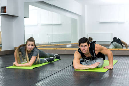 Young people doing exercises in gym together