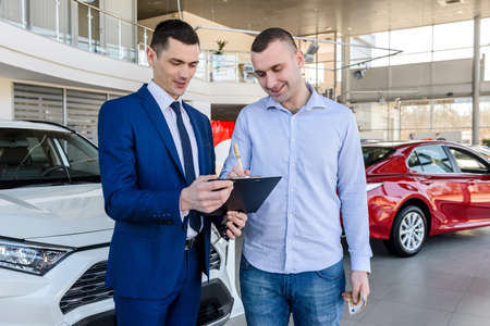 Salesman working with client in showroom, car buy operationの写真素材