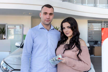 Happy family posing with car in showroom