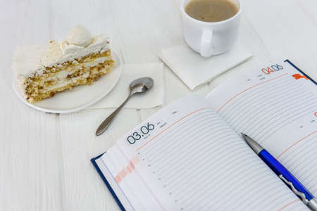Diary with cup of coffee and piece of cake