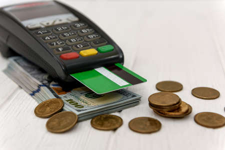 Dollars with coins and banking terminal with credit card