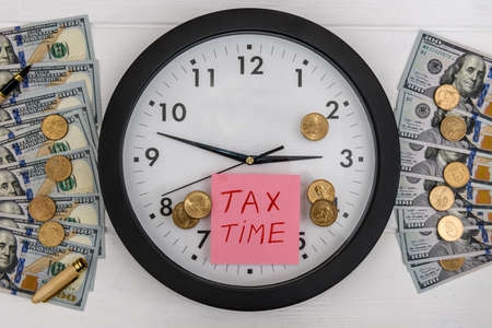 Clock with coins and dollar banknotes, tax timeの写真素材