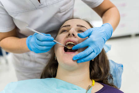 Dentist's hands in gloves with instrument and patientの写真素材