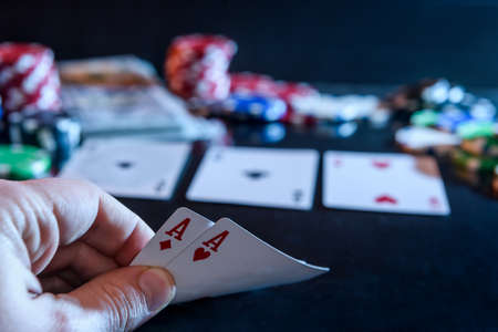 Two aces in hand and gambling chips at black