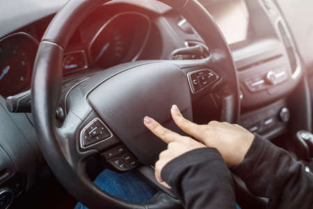 Female hands pointing with fingers on steering wheelの写真素材