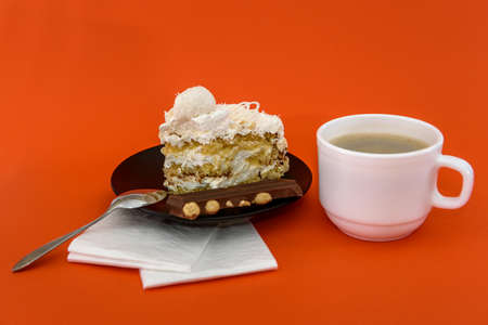 Cup with coffee and piece of cake at orange background