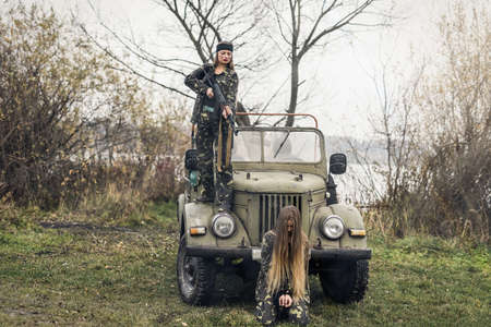 Woman soldier and her hostage against military car