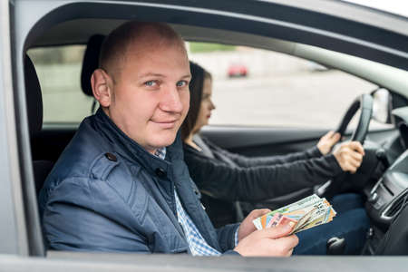Man holding euro banknotes sitting in car