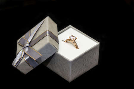 Golden ring with diamond in box isolated on black