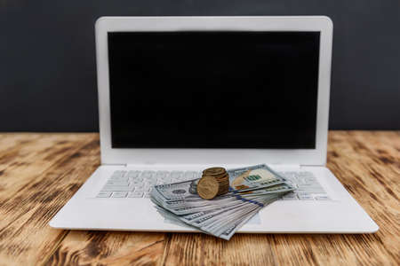 Laptop with dollars pile and golden coinsの写真素材