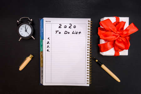 Clock with gift box and notepad on tableの写真素材