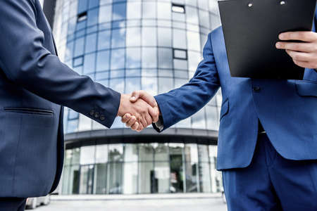 Colleagues handshaking before office building outdoors close up