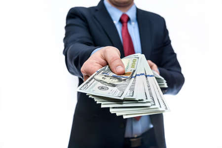 Man in business suit holds one hundred dollar denominations