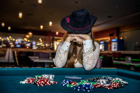 Woman in casino closing face with hands and hatの写真素材