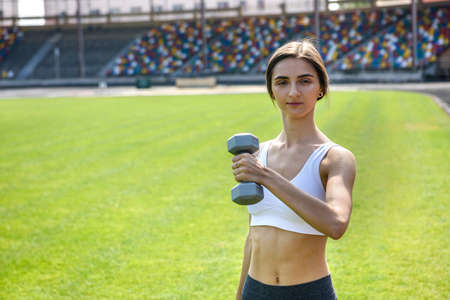 Woman doing fitness exercises. Young woman with dumbells posing outdoorsの写真素材