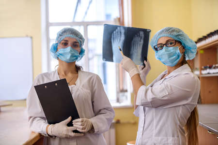 Two doctors with x-ray in medical laboratory posing for camera