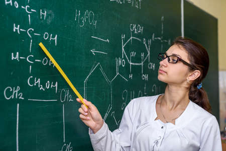 Chemical education. Woman near board explaining to students some materialの写真素材