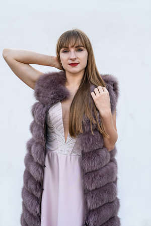 Beautiful young woman in fur coat on white wall. Beauty and fashion.の写真素材