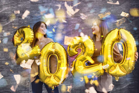 New year celebration concept. Two beautiful women with golden air balloons 2020の写真素材