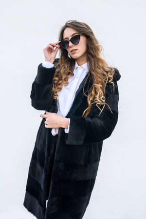 Fashion woman in fur coat and sunglasses posing outdoorsの写真素材