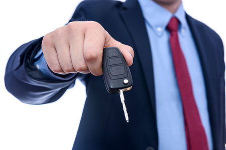 Man in suit holding car keys isolated on whiteの写真素材