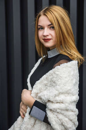Elegant woman in little black dress and with fur scarf posing outside. Fashion conceptの写真素材
