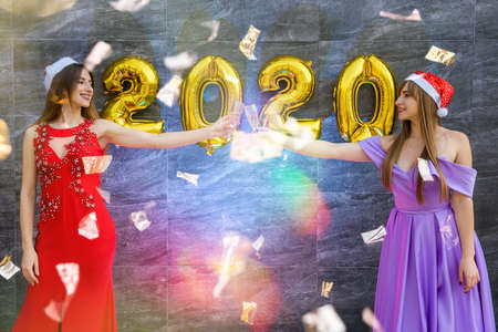 Portrait of two beautiful girls on the New Year's Eve wearing elegant evening dressesの写真素材