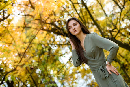 Female portrait. Brunette woman portrait in autumn park wearing olive dressの写真素材
