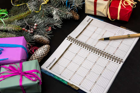 New year planning concept. Fir branches with colorful gift boxes on dark background